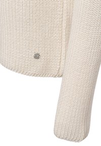 Gebreide crèmekleurige sweater met ribbelstructuur, voorzien van een metalen logo-accent bij de zoom en een aansluitend mouwontwerp.