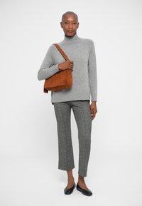 Siv turtleneck pulover, teksturirane sive hlače in črne balerinke. Rjava suede torbica dodaja kontrast. Preprost in moderen dizajn.