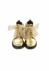 Botines metálicos dorados con superficie texturizada, suela de goma negra y cintas de seda doradas transparentes. Pequeñas pestañas en la parte posterior para facilitar su uso.