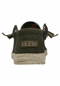 Scarpe slip-on in camoscio verde e rete con suola bianca maculata, dotate di linguette posteriori e logo "hey dude" sul tallone.