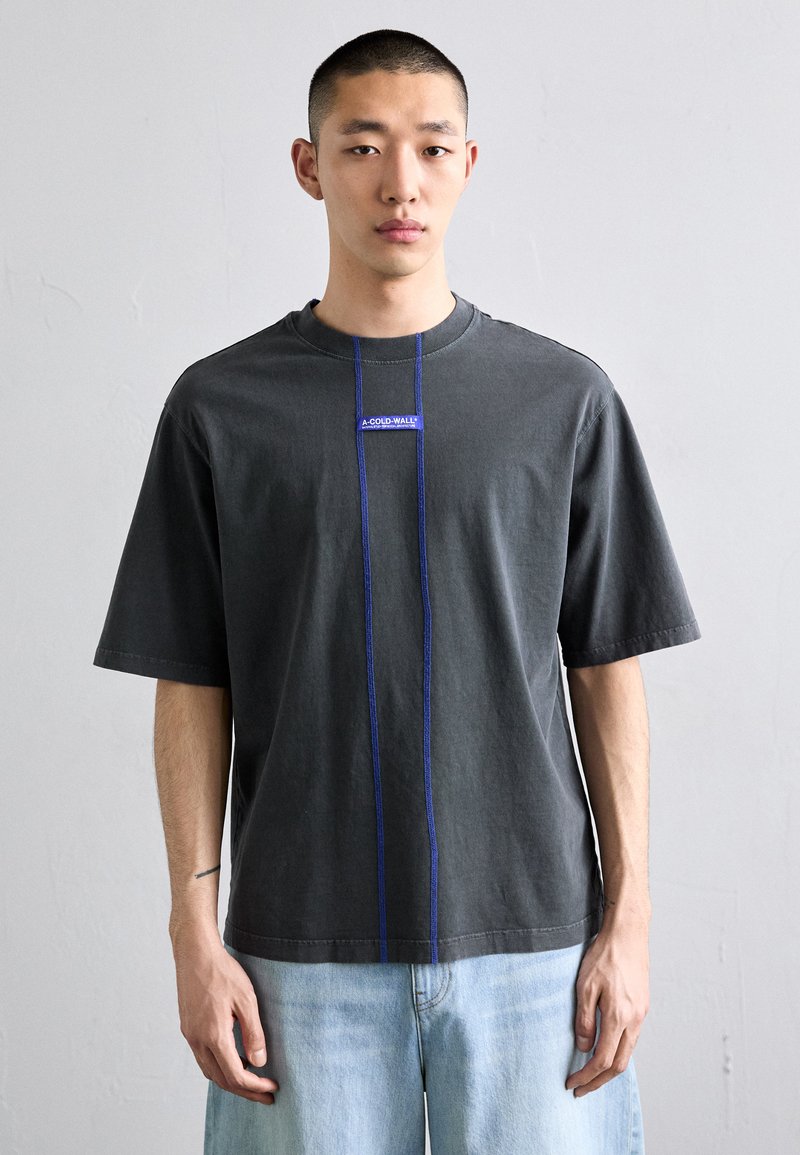 Men's gray cotton T-shirt with short sleeves, featuring a blue logo patch and contrasting blue stitching down the front. Casual fit.