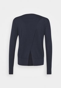 Pull à manches longues bleu marine, avec un design croisé dans le dos, une texture douce et un ourlet côtelé. Minimaliste, sans motifs ou accents supplémentaires.