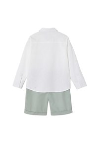 White linen long-sleeve shirt paired with green cotton shorts. The shirt features a collared neckline and buttoned cuffs; shorts have folded hems.