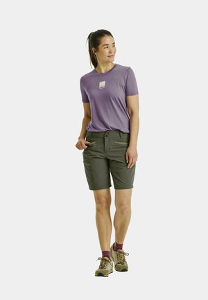 Short gray shorts with multiple pockets, paired with a light purple T-shirt featuring a small printed logo. The outfit is complemented by beige footwear.