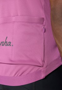Rosa Sportshirt mit einem Reißverschlusstaschen an der Seite, glatter Textur und abgerundetem Saum, mit "alpha." in Dunkelgrau auf der Vorderseite bedruckt.