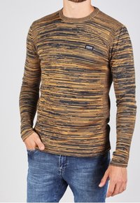 Długi rękaw swetra z okrągłym dekoltem w czarno-złoty pas w paski, z prążkowanymi mankietami i małą naszywką z logo na klatce piersiowej.