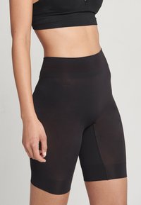 Svarta högmidjade cykelshorts gjorda av elastisk, slät tyg. Har en sömlös design med medellång längd till låret och en diskret midjeband.