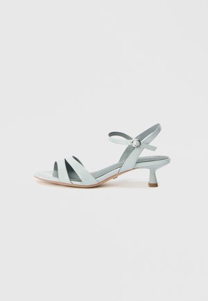 Light blue patent leather sandal with multiple crisscross straps, an ankle buckle, and a small, block heel. Smooth texture and minimal design.