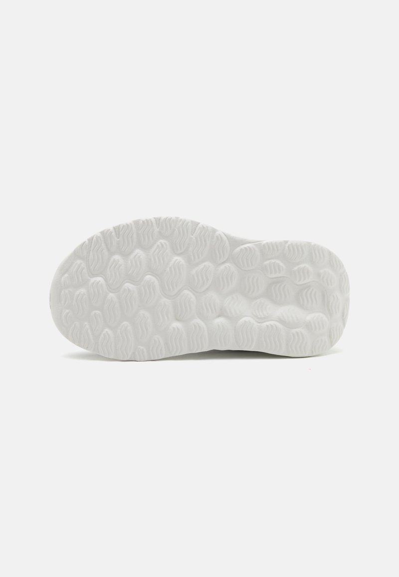 Suola di scarpa in gomma bianca caratterizzata da modelli di trazione testurizzati e un design ondulato, che mostra una finitura liscia e bordi arrotondati.