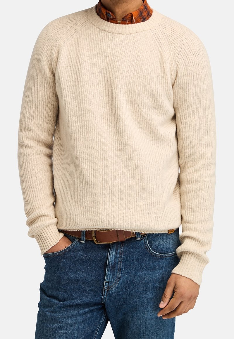 Maglione a coste color crema con scollo rotondo e maniche raglan, abbinato a una cintura marrone e jeans blu. Tessuto strutturato e silhouette aderente.