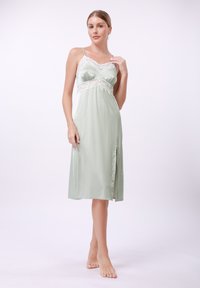 Rochie de noapte din satin verde mentă, cu dantelă, decolteu în V și fenta pe lateral. Dispune de bretele subțiri și o textură netedă, lucioasă.