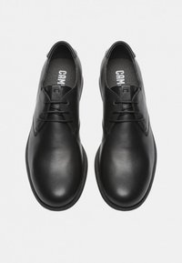 Pantofi din piele neagră cu un finisaj neted, având vârf rotund și design cu șireturi. Accente minime și talpă texturată neagră.