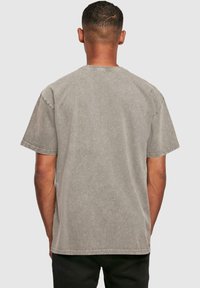 Grå bomulds t-shirt med en afslappet pasform, korte ærmer og rund halsudskæring. Stoffet har en falmet tekstur og synlige syninger.