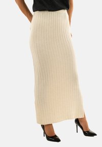 Gonna maxi beige a coste con alta vita, caratterizzata da strisce verticali e spacchi laterali. Abbinata a tacchi a punta neri.