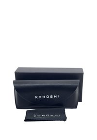 Funda de gafas de cuero negro con cierre de solapa redondeada, logo en relieve "KORŌSHI", acompañada de un paño de limpieza en color a juego.
