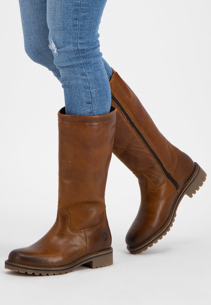 Bottes marron en cuir montant jusqu'au genou avec une finition texturée, une fermeture éclair latérale et une semelle robuste. Conçues avec un bout rond et des accents cousus.