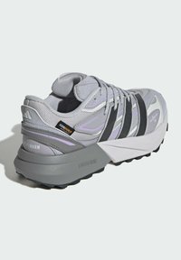 Gray athletic shoe featuring a textured upper, purple accents, black stripes, and a chunky white sole with “LIGHTSTRIKE” branding and a unique shape.