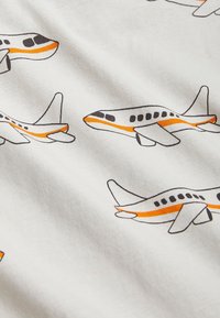 Tejido blanco con un patrón repetitivo de aviones estilizados en gris, negro y naranja, con detalles distintivos en las alas y la cola.