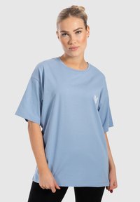 Lyseblå oversized t-shirt lavet af bomuld, med korte ærmer og et lille hvidt hjerte-logo på venstre brystområde.