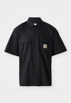 Must mustärg särg lühikirjul, valmistatud kootud kangast, millel on nööpidega esiosa, kaks rinnaTaskut ja väike oranž logo silt.