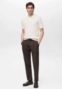 Knit polo shirt in off-white with short sleeves, paired with brown trousers and dark loafers. Fabric features a textured pattern.