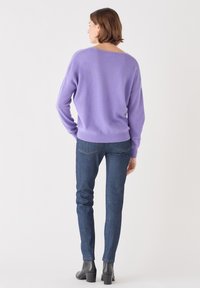 Lavendelstickad tröja med lös passform, bred halsringning och ribbade ärmar, kombinerad med mörkblå slim-fit-jeans och svarta ankelstövlar.