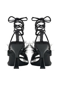 Schwarze High-Heel-Sandalen mit schmalen Riemchen, Federn am Absatz und Ausschnitten an den Seiten. Glänzende Oberfläche und schmaler Stiletto-Absatz.