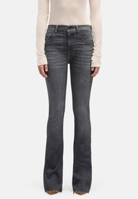 Ciemnoszare dzwony z wyblakłym wykończeniem, w pięciokieszeniowym stylu, z postrzępionym dołem. Nosi się je z jasnobeżową, długorękawową koszulą.