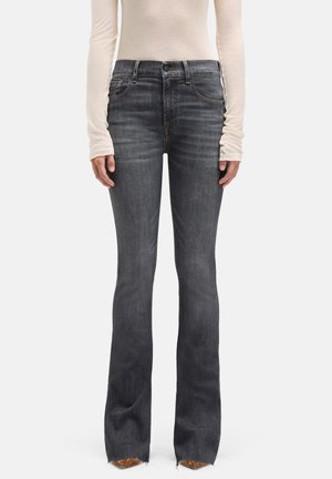 Mørkegrå vidde jeans med en falmet finish, fem-lomme design og frynset kant. Båret med en lysebeige langærmet skjorte.