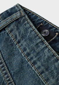 Primer plano de la cinturilla de unos jeans de mezclilla azul con un botón visible y costuras detalladas en la tela.