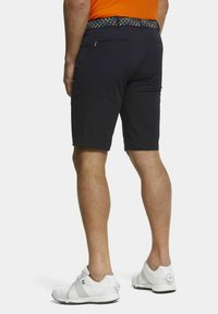 Marineblauwe shorts met een gladde textuur en een aansluitend ontwerp, voorzien van een kleurrijke gestreepte riem. Witte sportschoenen maken de outfit af.