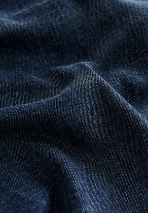 Dunkelblauer Denimstoff mit grober Textur, sichtbaren Webmustern und dezenten Farbnuancen im Gewebe.