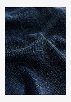 Dunkelblauer Denimstoff mit grober Textur, sichtbaren Webmustern und dezenten Farbnuancen im Gewebe.