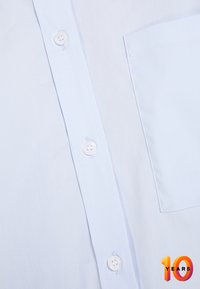 Light blue button-up shirt with a smooth texture, featuring white buttons, a chest pocket, and subtle stitching details. "10 Years" logo in bottom corner.
