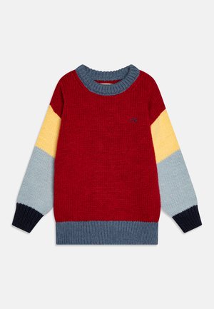 Rode gebreide trui met kleurvlakken in blauw, geel en grijs op de mouwen. Beschikt over een ribbelboord bij de ronde hals en mouwen, en een klein logo detail.
