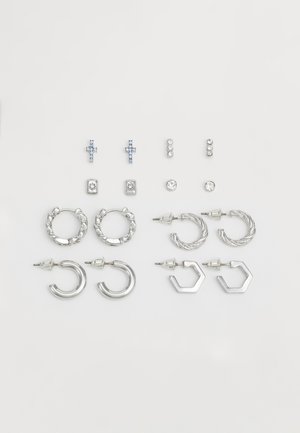 Juego de pendientes de plata que incluye aretes con forma de cruz, diseños de aros y acentos hexagonales, presentando diversas texturas y adornos.