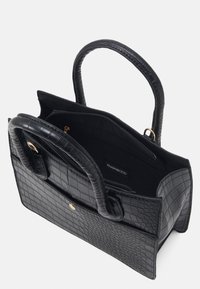 Czarna torebka z wytłaczanej skóry krokodyla o strukturalnym designie, z podwójnymi uchwytami i zamykaną na zamek kieszenią wewnętrzną, z elementami ozdobnymi w złotym kolorze.