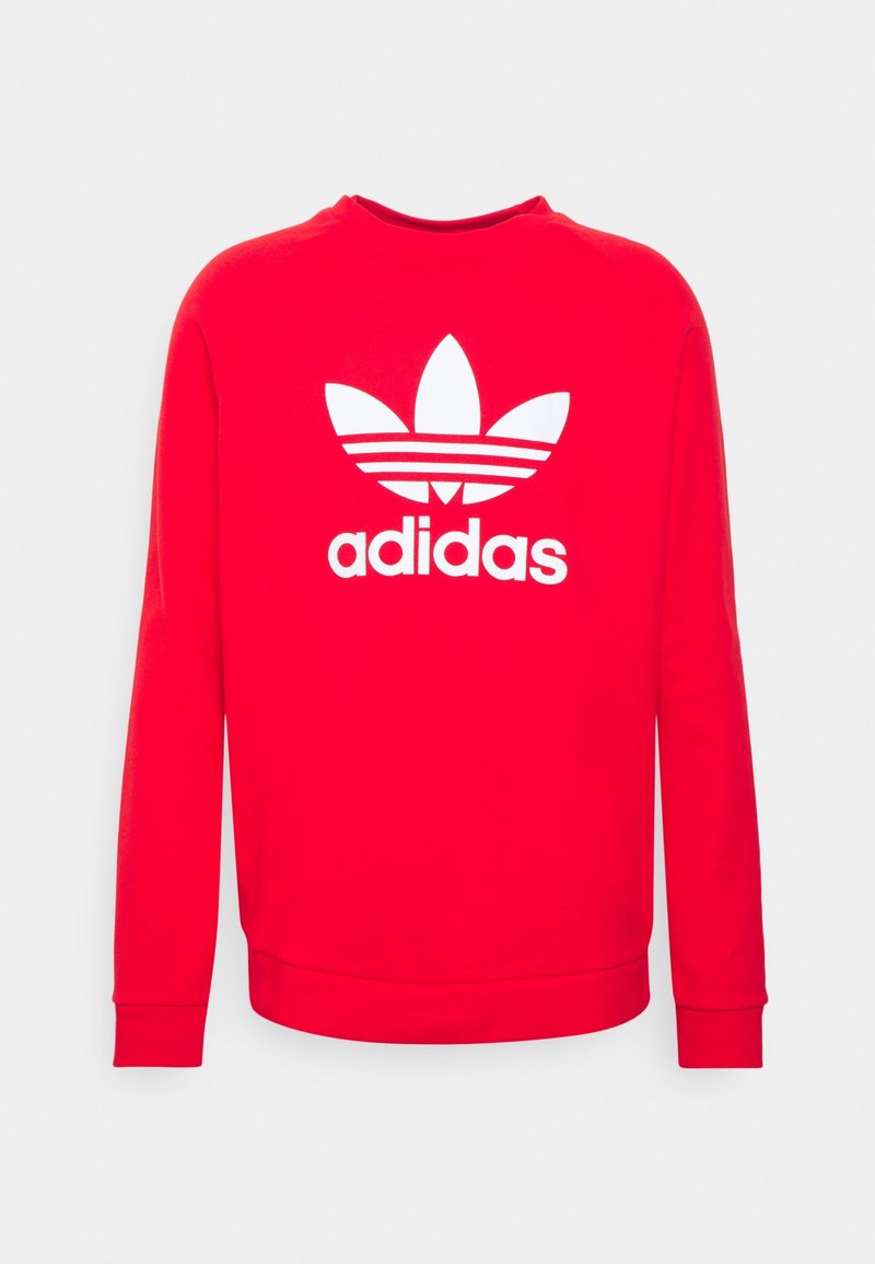 Red sweatshirt made of cotton, featuring long sleeves and a round neckline. Displays a large white Adidas logo with three stripes and leaf design.