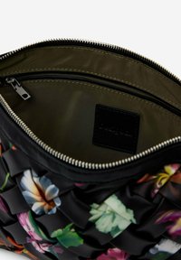 Borsa nera con motivo floreale, caratterizzata da un esterno testurizzato e plissettato. L'interno presenta un rivestimento verde e una tasca con zip. Finitura con zip argentata.