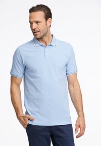 Polo de color azul claro hecho de algodón, con un cuello clásico, tapeta de tres botones y acentos a rayas en el cuello y las mangas.