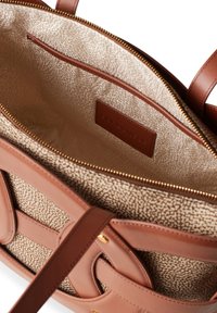 Tan and brown handbag with a textured interior. Features a gold zipper and brown leather accents. Includes a slip pocket and logo tag.