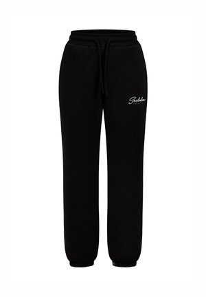Pantalons de survêtement noirs en tissu en coton doux, dotés d'une taille élastique avec cordon de serrage, d'anses resserrées aux chevilles et d'un logo blanc sur le devant.