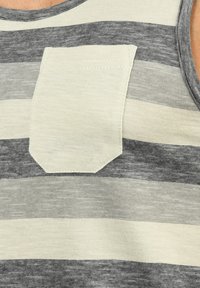 Grå og crème-stribet tanktop med en crème patch lomme; blødt stof, rund halsudskæring og fine horisontale linjer i teksturen.