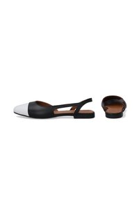 Schwarz-weiße Leder-Slingback-Ballerinas mit spitzer Zehenpartie, die ein ausgeschnittenes Riemendesign und eine braune, strukturierte Innensohle aufweisen.
