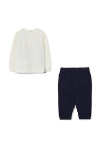 Crèmekleurige gebreide top met lange mouwen en drie knopen aan de achterkant, gecombineerd met marineblauwe geribde gebreide broek met een elastische tailleband.