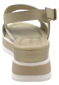 Sandalo con zeppa beige caratterizzato da una tomaia liscia, due cinturini regolabili e una suola bianca texturizzata. Soletta imbottita per il comfort.