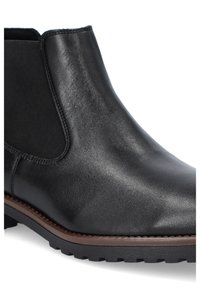 Czarne skórzane botki za kostkę z gładkim wykończeniem, elastycznymi bokami i solidną gumową podeszwą z brązowym akcentem na dole.