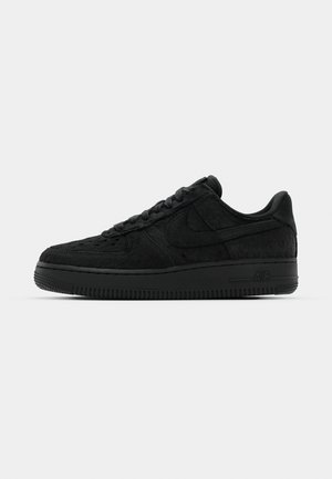 Zwarte Nike Air Force 1 sneakers hebben een gestructureerde bovenkant, gladde leren accenten, platte veters en een dikke rubberen zool met ribbeldetails.
