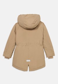 Beige pufferjakke med hette og elastisk midje. Har en litt forlenget bakside og strikkede mansjetter. Merke nederst på ryggen.