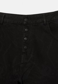 Close-up of black denim pants with four metal buttons along the front fly and belt loops at the waistband.